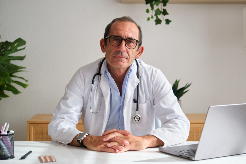Doctor concerned about his net worth sitting at desk 
